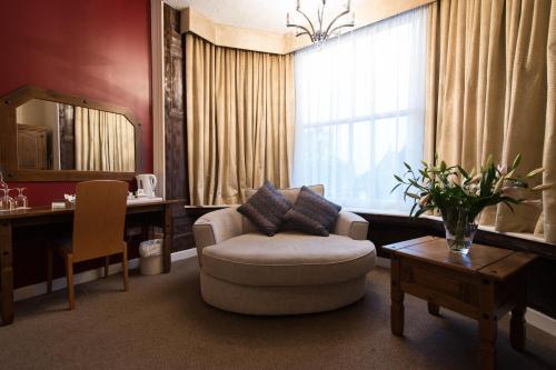 a living room with a chair and a table and a mirror at The Pearl Hotel in Peterborough