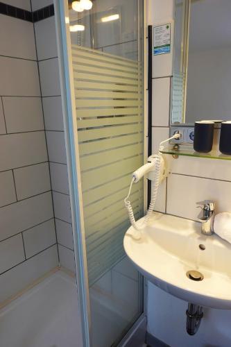 a bathroom with a sink and a shower at Hotel Berghof Wasserkuppe & Gästehaus Fuldaquelle in Gersfeld