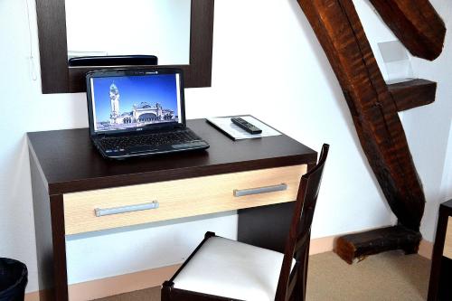 a laptop computer sitting on top of a wooden desk at Hotel Les Bénédictins in Limoges
