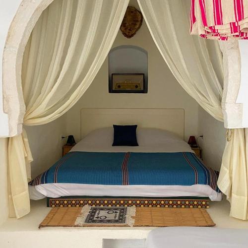a bedroom with a bed with curtains and a rug at Houch ZanZouri in Houmt Souk