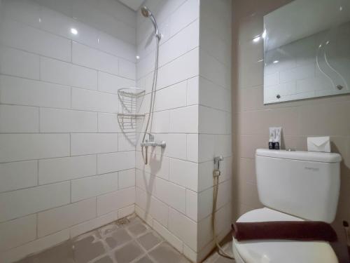a white bathroom with a shower and a toilet at Homey and Good Studio Taman Melati Sinduadi Apartment By Travelio in Kejayan