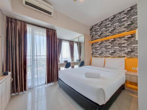 a hotel room with a bed and a large window at Homey and Good Studio Taman Melati Sinduadi Apartment By Travelio in Kejayan
