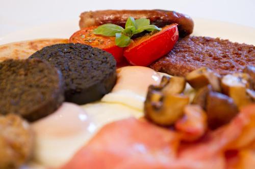 a plate of food with eggs sausage and tomatoes at Arden Country House in Linlithgow