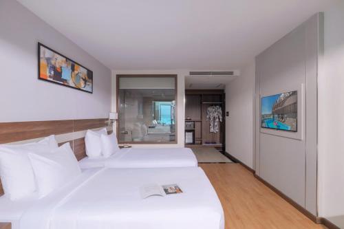 two beds in a hotel room with white walls at PANAMA Nha Trang Hotel in Nha Trang