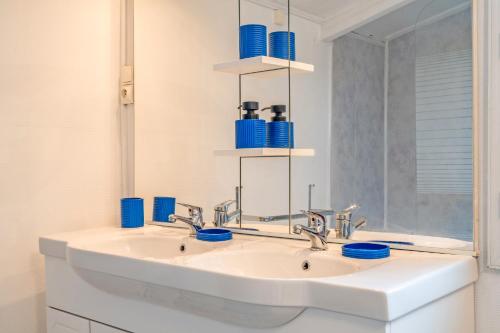 a bathroom with a sink with blue cups on it at Ty Abéric maison en front de mer in Ploudalmézeau