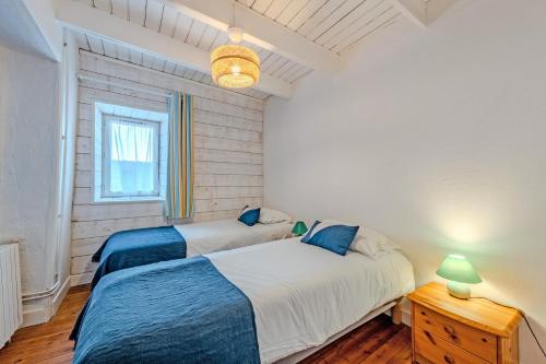 a bedroom with two beds and a table and a window at Ty Abéric maison en front de mer in Ploudalmézeau
