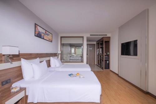 a bedroom with a large white bed and a television at PANAMA Nha Trang Hotel in Nha Trang