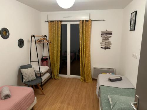 a room with a bed and a chair and a window at Maison le palmier in Troarn