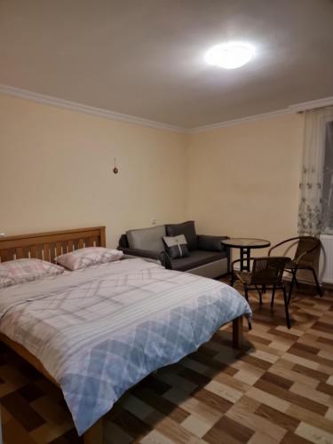 a bedroom with a bed and a couch and a table at Mia House in Borjomi