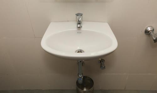 a white sink in the corner of a bathroom at Treebo Sapphire Studio in Nashik