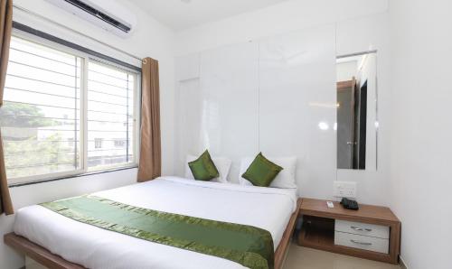a white bedroom with a bed and a window at Treebo Sapphire Studio in Nashik