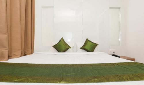 a bedroom with a white bed with green pillows at Treebo Sapphire Studio in Nashik