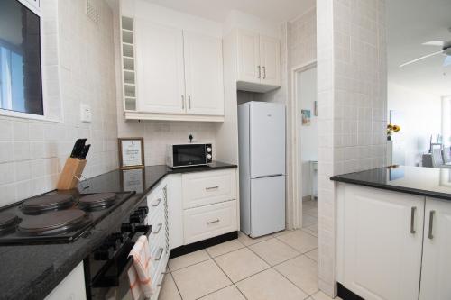 a kitchen with white cabinets and a white refrigerator at 72 Sea Lodge Umhlanga Rocks in Durban