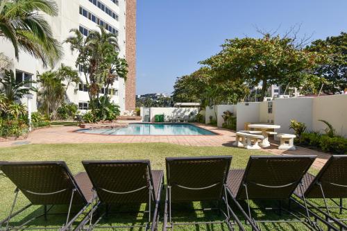 a yard with chairs and a pool in a building at 72 Sea Lodge Umhlanga Rocks in Durban
