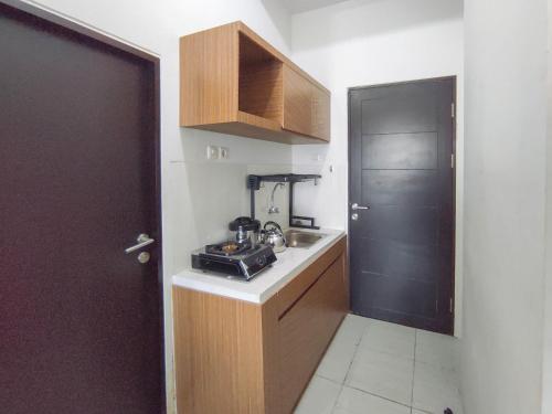 a small kitchen with a sink and a black door at Homey Studio with Easy Pool Access Apartment at Suncity Residence By Travelio in Sidoarjo