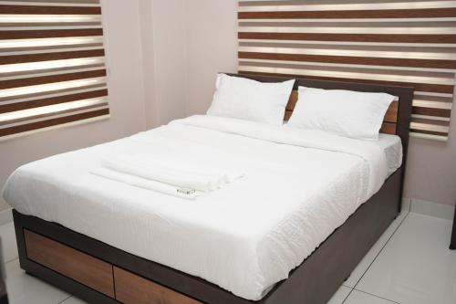 a bed with white sheets and a wooden headboard at Eagle Nest Residency in Perintalmanna