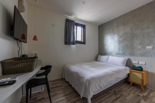 a small room with a bed and a desk and a television at 鄉都文旅 in Jiaoxi