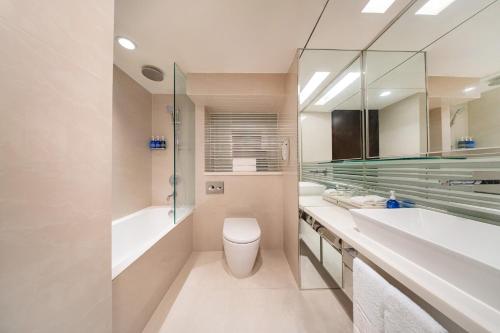 a bathroom with a toilet and a tub and a sink at Regal Oriental Hotel in Hong Kong