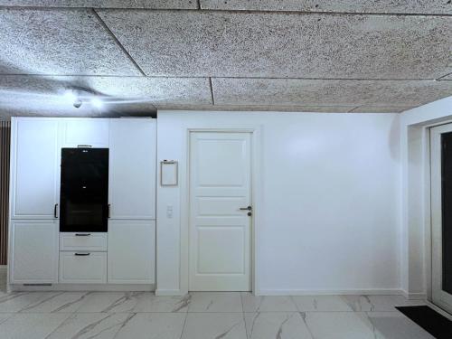 a room with white walls and a door and a tv at Cozy Coastal Home in Egernsund in Egernsund