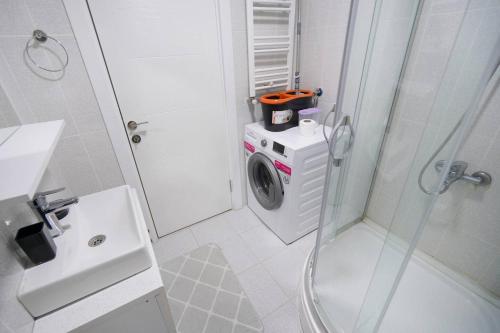 ein weißes Bad mit einer Waschmaschine in der Dusche in der Unterkunft Classic Suite SH17 in Esenyurt