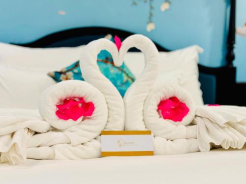 two towels shaped like swans sitting on a bed at The ORCHID PREMIUM Hotel in Hue