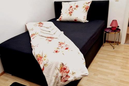 a bed with a black frame with a flower blanket on it at Ruhiges und großzügiges Appartement in Sankt Valentin