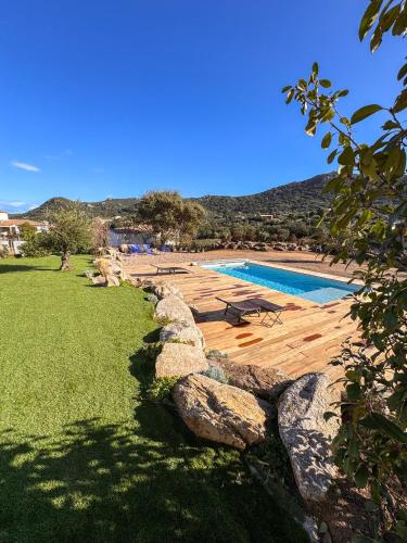 une piscine avec une terrasse en bois et une piscine dans l'établissement Casa Cagna Piscine et jacuzzi, à Figari