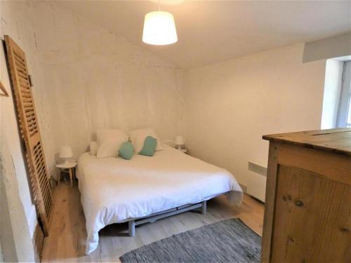 a small bedroom with a white bed with two pillows at capbat in Commensacq