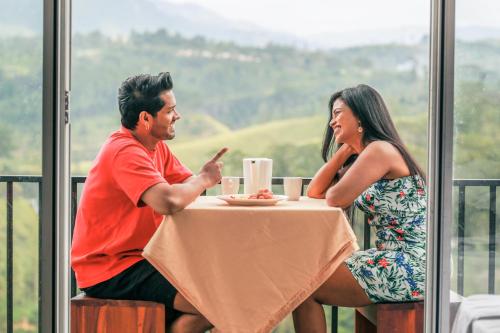 a man and a woman sitting at a table at Wild Flower Waterfall Villa in Talawakele