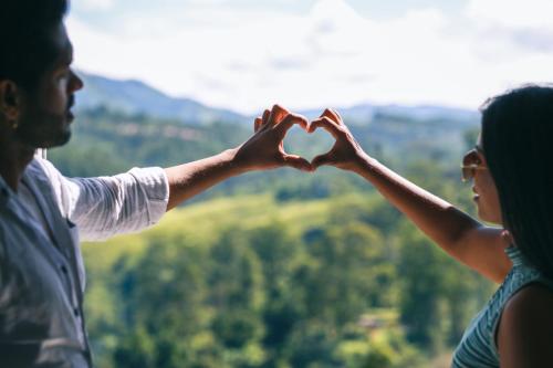 a man and a woman making a heart made out of their hands at Wild Flower Waterfall Villa in Talawakele