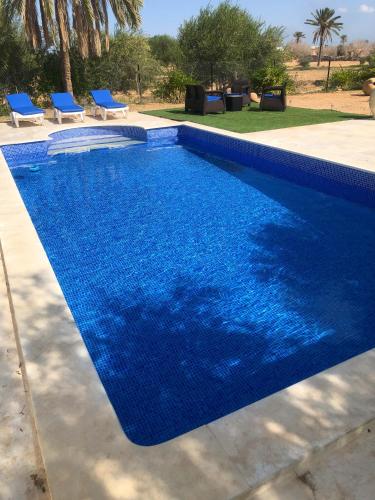 a blue swimming pool with two blue chairs next to it at Villa Walegh in Ouallarh