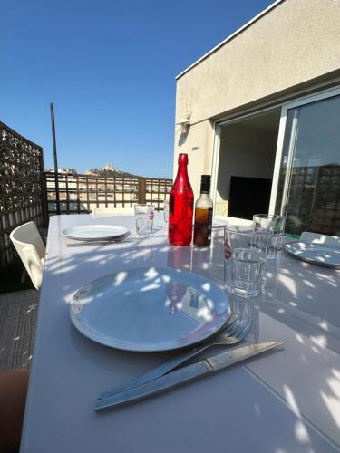 - une table avec des assiettes, des verres et une bouteille de vin dans l'établissement Stunning rooftop, near Cours Julien, à Marseille