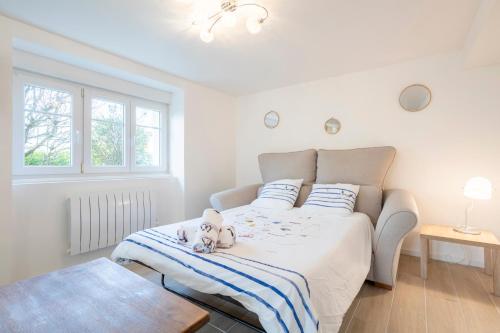 a small dog sitting on a bed in a bedroom at T2 avec jardin 1,2km de la plage in Bénodet