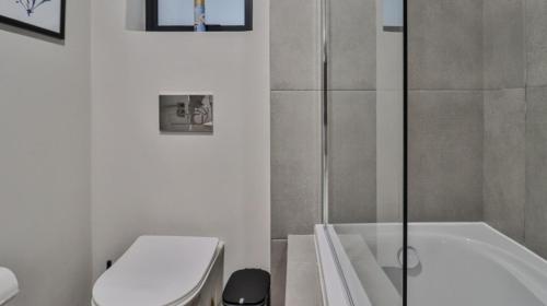 a bathroom with a tub and a toilet and a sink at 105 Mossel Cove Unique & Trendy in Mossel Bay