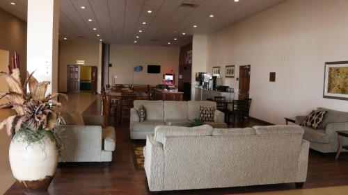 a living room with couches and a table and a kitchen at Astoria Hotel & Event Center in Dickinson