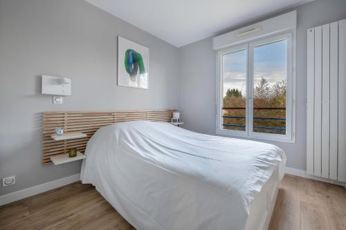 une chambre blanche avec un lit et une fenêtre dans l'établissement La Baule, appartement confortable pour 4, à Pornichet