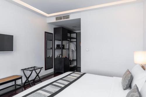 a bedroom with a white bed and a black cabinet at Souphattra Hotel Luang Prabang in Luang Prabang