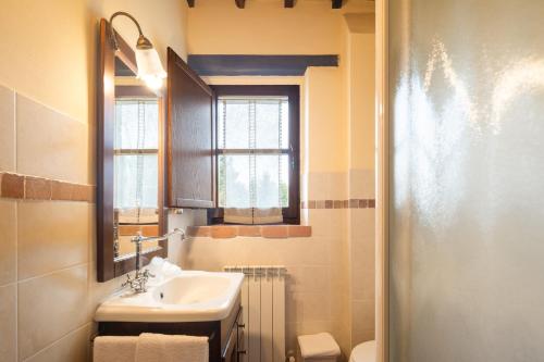 a bathroom with a sink and a mirror and a toilet at Casale delle Lucrezie by VacaVilla in Due Santi