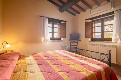a bedroom with a bed with a colorful quilt at Casale delle Lucrezie by VacaVilla in Due Santi