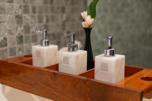 three white soap dispensers in a wooden tray at Souphattra Hotel Luang Prabang in Luang Prabang