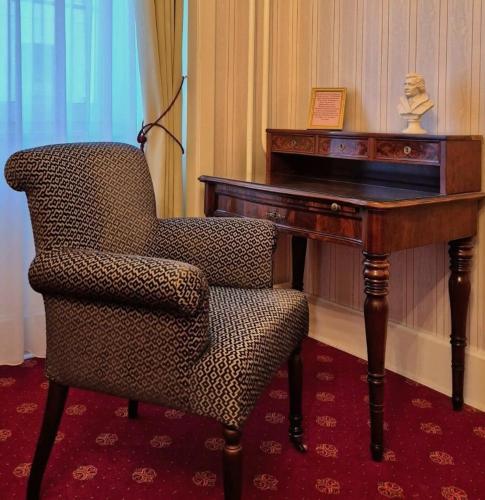 a chair sitting next to a wooden desk with a desk at Boutique-Hotel Amalienhof in Weimar