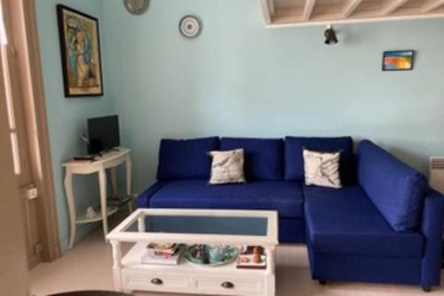 un canapé bleu dans un salon avec une table dans l'établissement Studio in a 19th century villa with parking, à Villers-sur-Mer