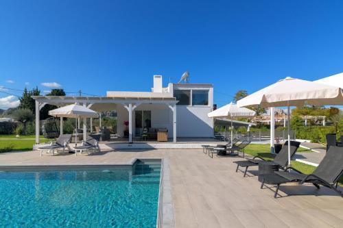 a villa with a swimming pool and umbrellas at Casa Bianca Villa in Kolimbia
