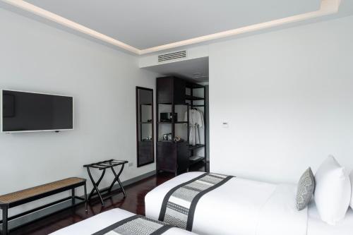 a bedroom with two beds and a flat screen tv at Souphattra Hotel Luang Prabang in Luang Prabang