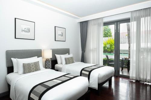 a hotel room with two beds and a balcony at Souphattra Hotel Luang Prabang in Luang Prabang