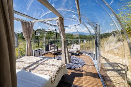 a room with a bed in a glass house at Bubble Perseus in Monsampolo del Tronto