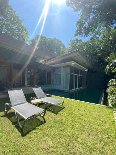 two lawn chairs sitting in the grass in front of a house at Ambong Pool Villas - Private Pool in Pantai Cenang