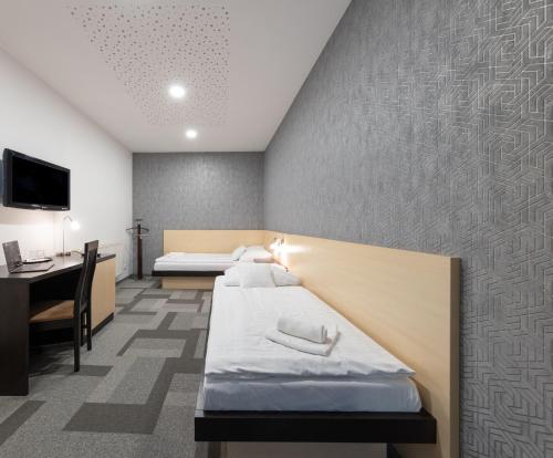 a hotel room with two beds and a desk at BNC Hotel - Restaurant - Bowling in Bratislava