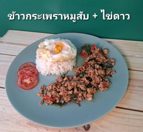 a plate of food with rice and an egg and tomatoes at Casa Coco Hotel in Nakhon Ratchasima