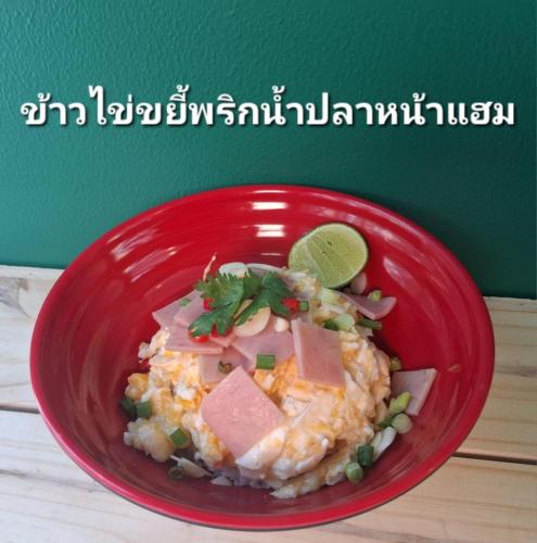 a red bowl of food with meat and a lime at Casa Coco Hotel in Nakhon Ratchasima